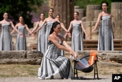 Actress Mary Mina, playing a priestess, lights the flame during the final dress rehearsal of the flame lighting ceremony for the Paris Olympics, at the Ancient Olympia site, Greece, April 15, 2024.