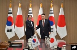 Presiden Korea Selatan Yoon Suk Yeol (kanan) berjabat tangan dengan Perdana Menteri Jepang Fumio Kishida saat bertemu di kantor kepresidenan di Seoul, Minggu, 7 Mei 2023. (Foto: Jung Yeon-je via REUTERS)