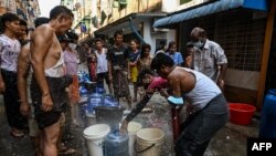 မီးမလာတဲ့အတွက် ရေပြတ်လပ်မှုနဲ့ကြုံနေရတဲ့ ရန်ကုန်မြို့ခံတချို့ ပရဟိတအသင်းတခုရဲ့ ရေအလှူကိုစောင့်ဆိုင်းနေစဉ် (မတ် ၁၄၊ ၂၀၂၂)