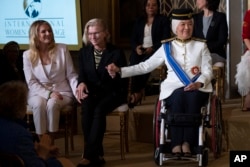 Ukrainian medic Yuliia Paievska, Polish journalist Bianka Zalewska, left, and Malaysian Senator Datuk Ras Adiba Radzi, right, hold hands as Paievska is recognized during the International Women of Courage Award ceremony hosted by first lady Jill Biden and Secretary of State Antony Blinken in the White House on March 8, 2023. (Manuel Balce Ceneta/AP)