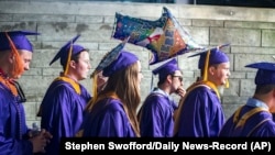 FILE - James Madison University students walk to commencement in Harrisonburg, Va., May 5, 2017. The school is participating in Welcome Corps on Campus, a federal refugee resettlement and education program. (Stephen Swofford/Daily News-Record Via AP)