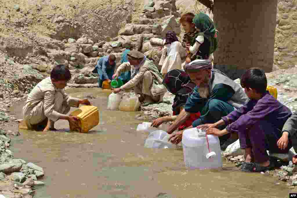 Afghans fill cans with water from a stream at a flood affected area in Burka district of Baghlan province.