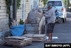 Seorang pemulung mengikat kardus-kardus karton untuk dijual di tempat-tempat daur ulang di Jakarta, 22 Februari 2022. (Foto: Bay Ismoyo/AFP)