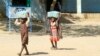 FILE - Children carry packs of humanitarian aid at a school housing displaced Sudanese who had fled violence in their war-torn country, near Gedaref, March 10, 2024.