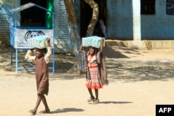 FILE - Children carry bags of humanitarian aid at a school near Gedarif that hosts displaced Sudanese fleeing violence in the war-torn country, March 10, 2024.