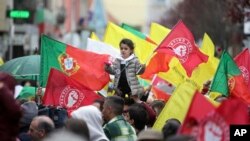 A child holding a flower and a Socialist Party flag is lifted above the crowd during an election campaign action with the Socialist Party leader Pedro Nuno Santos on the street in the Lisbon suburb of Moscavide, March 8, 2024.