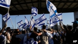 Para pengunjuk rasa mengibarkan bendera nasional Israel untuk memberi mendukung kepada para prajurit yang diinterogasi atas penyiksaan tahanan, di luar pangkalan militer Sde Teiman, Senin, 29 Juli 2024. (Tsafrir Abayov/AP)