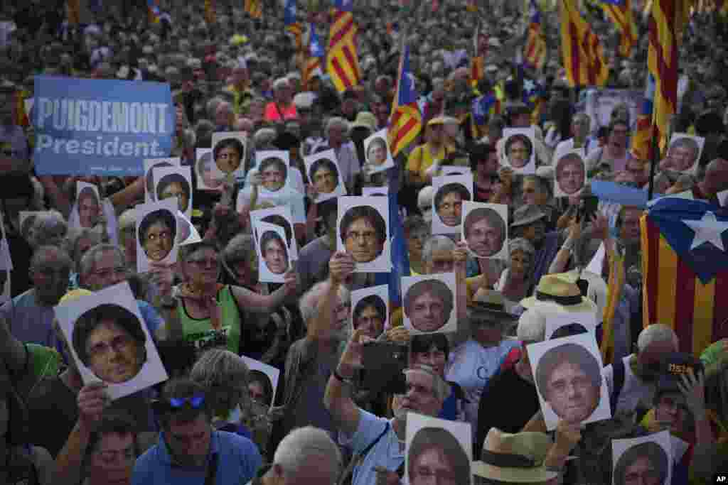 Para pendukung pemimpin kemerdekaan Catalan Carles Puigdemont memegang potretnya saat menunggu kedatangannya di dekat parlemen Catalan untuk menghadiri debat di kota Barcelona, ​​Spanyol. (AP)&nbsp;