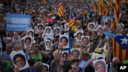 Supporters of Catalan independence leader Carles Puigdemont hold his portrait as they wait for his arrival near the Catalan parliament to allegedly attend the investiture debate in Barcelona, Spain.