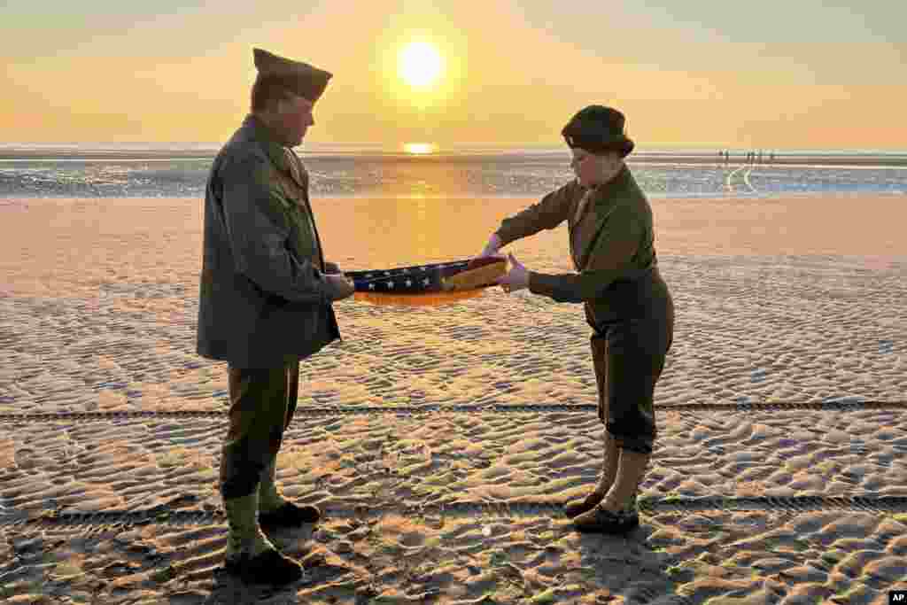 Christophe Receveur y su hija Julie, de Francia, despliegan una bandera estadounidense que él compró hace seis meses en Gettysburg, Pensilvania, para conmemorar el Día D, el jueves 6 de junio de 2024 en Utah Beach, Normandía.