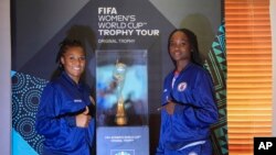 FILE: Haitian goalkeeper Kerly Theus, left, and fellow teammate Esthericove Joseph, post alongside the Women’s World Cup trophy in Port-au-Prince, Haiti, Saturday, April 15, 2023. A FIFA delegation is showing the trophy to all 32 nations participating in the tournament.