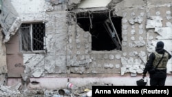 (FILE) A Ukrainian war crime prosecutor inspects a building damaged by a Russian military strike.