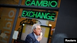 Un peatón come un helado mientras pasa frente a una tienda de cambio, en el distrito financiero de Buenos Aires, Argentina, 26 de abril de 2023. REUTERS/Agustin Marcarian