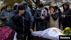 ফাইল ছবি—রোজা গ্রামে রুশ রকেট হামলায় নিহত দুজনের মরোদেহের সামনে তাদের আত্মীয়দের দেখা যাচ্ছে। (৯ অক্টোবর, ২০২৩) 