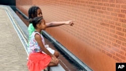 Gabriella Jackson, 7, and Erica Jackson, 9, look for familiar names on the National Monument to Freedom in Montgomery, Alabama, June 19, 2024. The monument is inscribed with 122,000 surnames that formerly enslaved people chose for themselves after being emancipated.