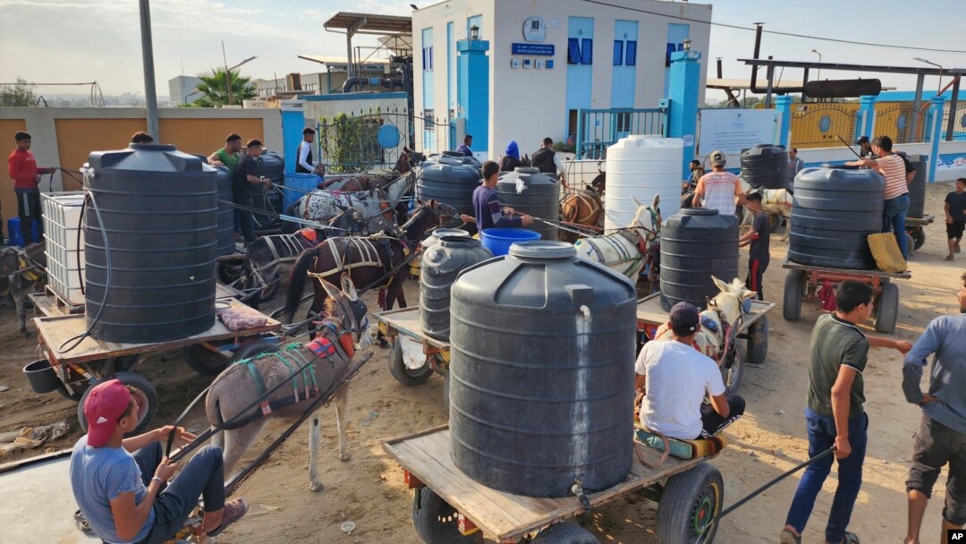 Palestinians queue to collect drinking water from a water treatment station in the central Gaza Strip to distribute to displaced people at shelters, in Deir al Balah, Gaza Strip, Oct. 27, 2023.