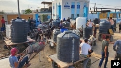Palestinians queue to collect drinking water from a water treatment station in the central Gaza Strip to distribute to displaced people at shelters, in Deir al Balah, Gaza Strip, Oct. 27, 2023.