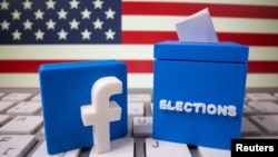 A 3D printed elections box and Facebook logo are placed on a keyboard in front of U.S. flag in this illustration.