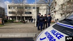 Polisi dan jurnalis berdiri di luar kantor polisi La Courneuve, pinggiran utara Paris, 18 Maret 2024, sehari setelah kantor tersebut menjadi sasaran serangan kembang api. Sembilan orang dilaporkan telah ditangkap terkait serangan tersebut. (Clotilde GOURLET / AFP)