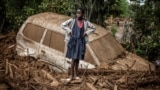 A girl looks on next to a damaged car buried in mud in an area heavily affected by torrential rains and flash floods in the village of Kamuchiri, near Mai Mahiu, Kenya, April 29, 2024. 