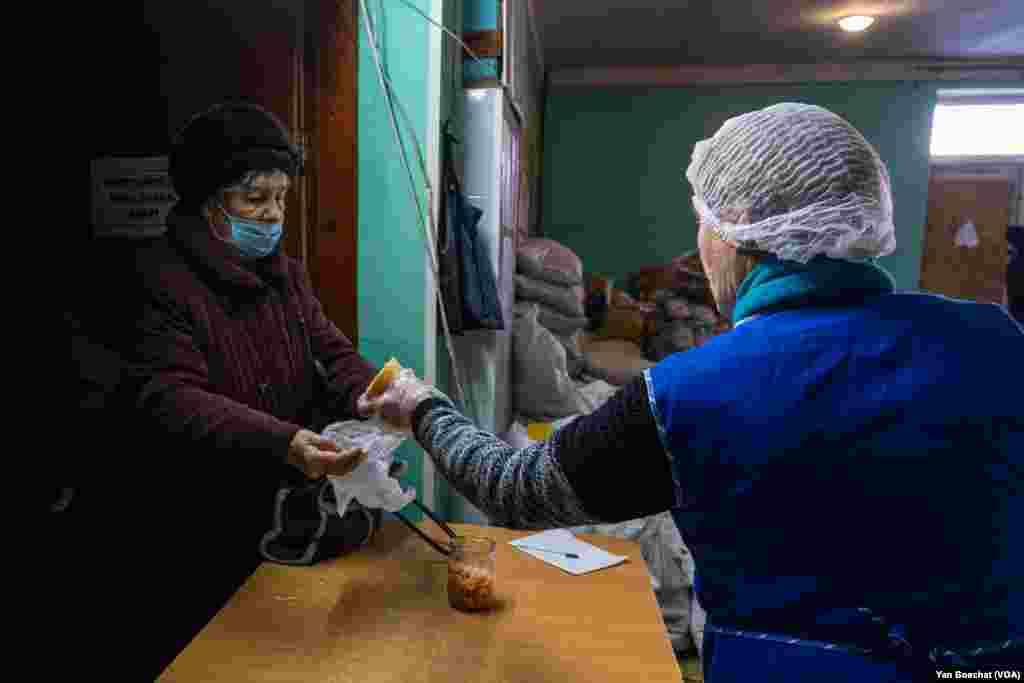 An elderly woman receives food in a humanitarian kitchen in Kupiansk, Feb. 17, 2023. For many here, the kitchen is the only source of food.