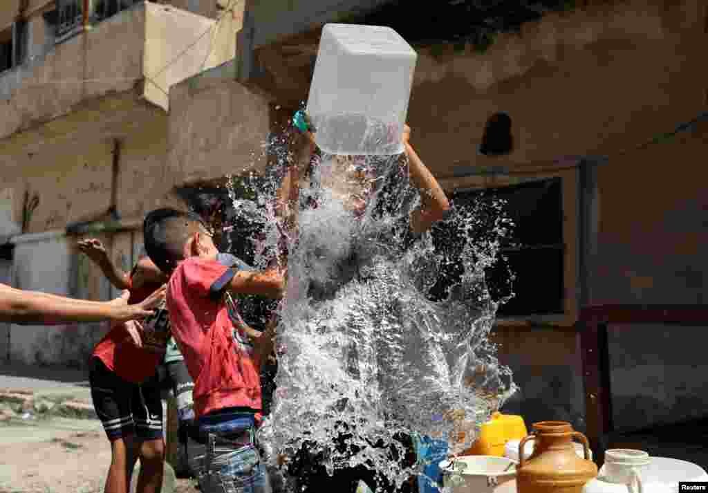 Children play as they fill plastic containers with water in the northeastern city of Hasaka, Syria.