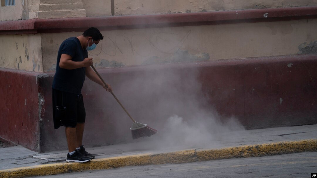 A man sweeps up volcanic ash spewed from the Popocatepetl volcano, in Atlixco, Mexico, May 24, 2023.