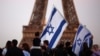 Supporters of Israel hold flags as they protest following Hamas' biggest attack on Israel in years, in Paris, France, Oct. 9, 2023, with the Eiffel Tower in the background.