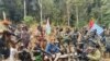Seorang pria yang diidentifikasikan sebagai Philip Mehrtens, pilot Selandia Baru yang disebut-sebut disandera oleh kelompok pro-kemerdekaan, duduk di antara para pejuang separatis di wilayah Papua Indonesia, 6 Maret 2023. (TPNPB/Handout via REUTERS)