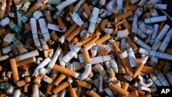 FILE - Cigarette butts fill a smoking receptacle outside a federal building in Washington, April 15, 2021. According to government survey data released April 27, 2023, U.S. adults are smoking less.