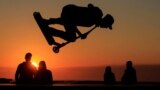 A young man performs a trick on a scooter during the sunset at a skate park on the sea wall of Calais, France, Aug. 15, 2023. 