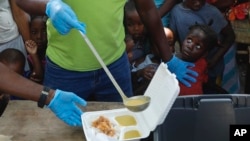 FILE - A server ladles soup into a container as children line up to receive food at a shelter for families displaced by gang violence, in Port-au-Prince, Haiti, March 14, 2024.