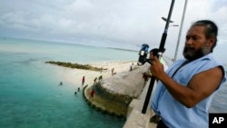 FILE - A man fishes on a bridge on Tarawa atoll, Kiribati, on March 30, 2004. 