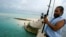 FILE - A man fishes on a bridge on Tarawa atoll, Kiribati, on March 30, 2004. 