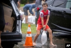 Brantley Schnabel helps his family carry sandbags to their van while preparing for Hurricane Debby at a county park, Aug. 5, 2024, in Savannah, Georgia.