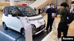 FILE - A salesman speaks about the Chinese-made Wuling Air EV electric car to visitors at a shopping mall in Jakarta, Indonesia, Feb. 5, 2023.