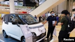 资料照片：在雅加达一家购物中心，一名推销员向顾客介绍中国制造的五菱电动汽车。(2023年2月5日）