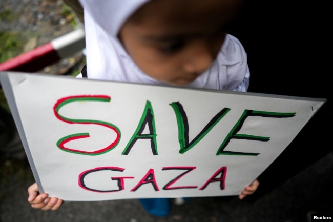 A child holds a SAVE GAZA sign during a pro-Palestinian rally in front of the Israeli Embassy in Bangkok, Oct. 21, 2023.