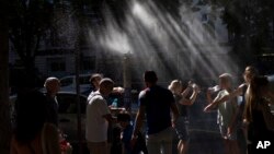 People cool off under a misting fountain while filling their water bottles on a hot afternoon during the 2024 Summer Olympics, in Paris, France, July 29, 2024.