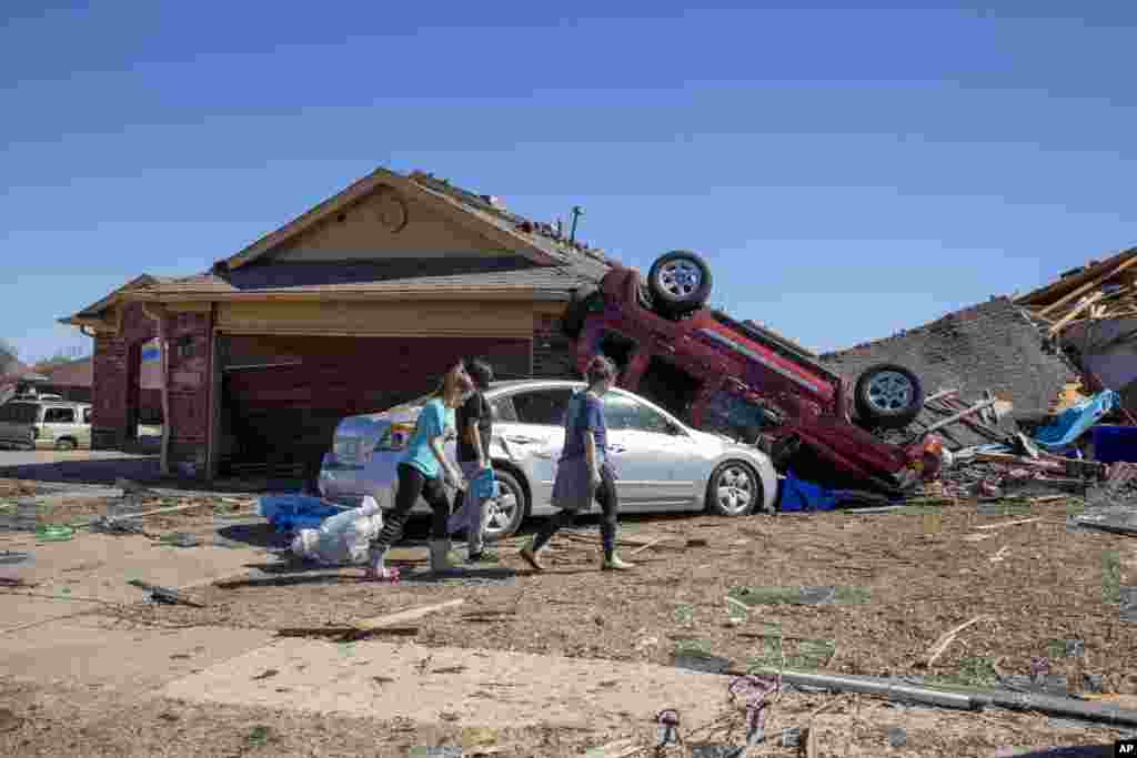 Neighbors walk in front of a home damaged at Wheatland Drive and Conway Drive, Feb. 27, 2023 in Norman, Oklahoma, after severe storms and tornadoes moved through the area overnight.