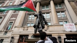 Студент с палестинским флагом у входа в Гамильтон-холл на кампусе Колумбийского университета в Нью-Йорке. 30 апреля 2024 года. (Mary Altaffer/Pool via Reuters).