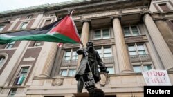 Seorang mahasiswa berpawai sambil membawa bendera Palestina di luar gedung Hamilton Hall di kampus Columbia University di New York, Selasa, 30 April 2024. (Foto: Mary Altaffer/Pool via Reuters)