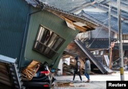 Warga berjalan melewati rumah yang rusak akibat gempa, di Nanao, prefektur Ishikawa, Jepang, 2 Januari 2024. (Foto: REUTERS/Kim Kyung-Hoon)