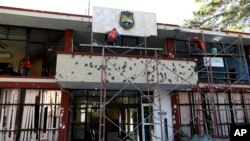 FILE - Workers repair the entrance of City Hall riddled with bullet holes in Villa Union, Mexico, Dec. 2, 2019, after 22 people were killed in a weekend gun battle between a drug cartel and security forces.