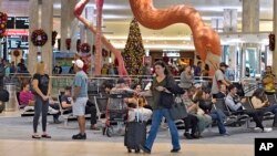 Holiday travelers pass by "Phoebe" the Flamingo at the Tampa International Airport, Dec. 22, 2023, in Tampa, Fla.