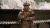 A Ukrainian serviceman about to rotate back into the front line stands by an armored transporter outside Kupiansk, Ukraine, Feb. 18, 2023.