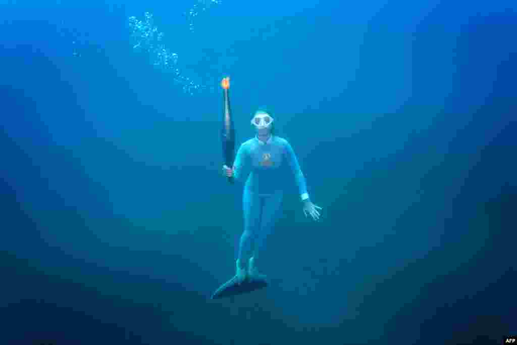 In this handout photograph taken and released by The Paris 2024 press service, French freediver champion Alice Modolo holds the Olympic torch underwater in the Mediterranean Sea as part of the Olympic torch relay in Villefranche-sur-mer, ahead of the Paris 2024 Olympic Games.