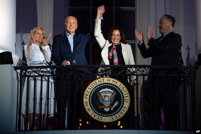 FILE - First lady Jill Biden and second gentleman Douglass Emhoff watch as President Joe Biden raises the hand of Vice President Kamala Harris while they view the Independence Day firework display from the White House, on July 4, 2024, in Washington. (AP Photo/Evan Vucci)