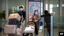 Sejumlah pelancong mengenakan masker saat tiba di area kedatangan Bandara Internasional Beijing pada 26 April 2023. (Foto: AP/Mark Schiefelbein)