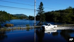 Sebuah mobil tampak melaju di jalan yang tergenang air akibat badai lee yang melanda wilayah Northeast Harbor, Maine, pada 17 September 2023. (Foto: AP/Robert F. Bukaty)